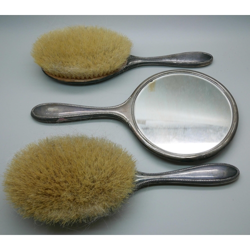 7336 - Two silver back brushes and a hand mirror by Walker & Hall