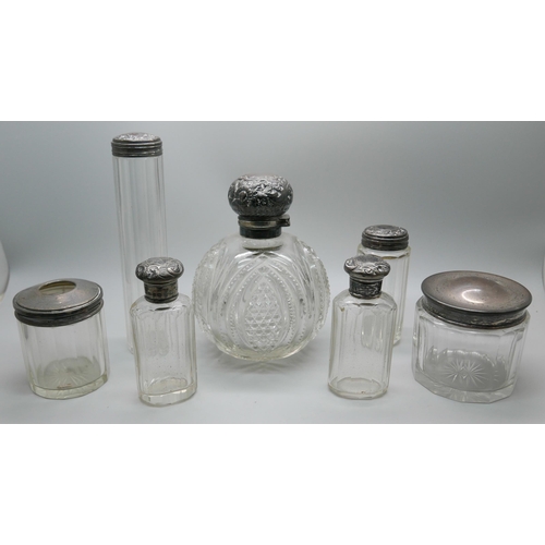 7337 - A silver topped globular glass scent bottle, hinge requires repair, and six silver topped glass bott... 