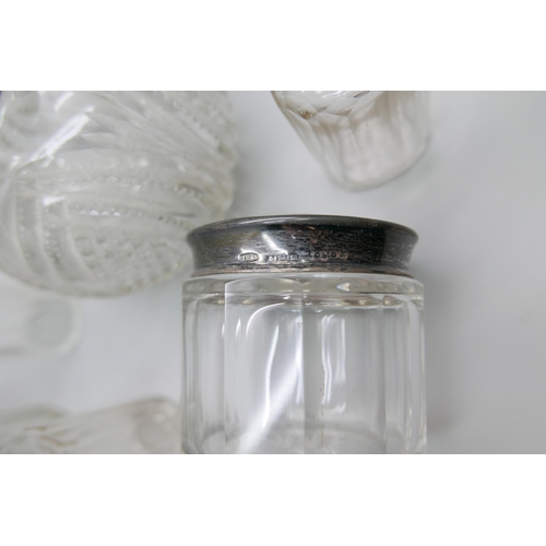 7337 - A silver topped globular glass scent bottle, hinge requires repair, and six silver topped glass bott... 