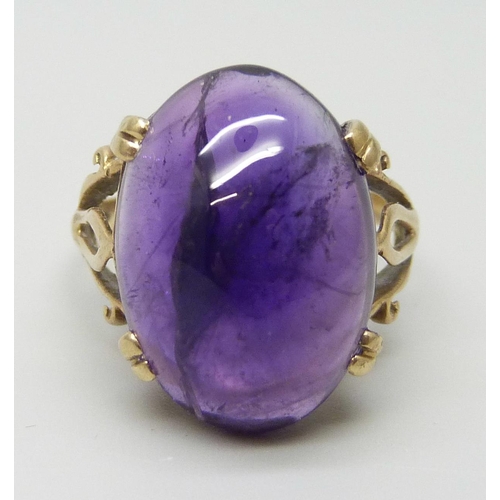 7005 - A 9ct gold ring set with a purple cabochon stone, 4.8g, L