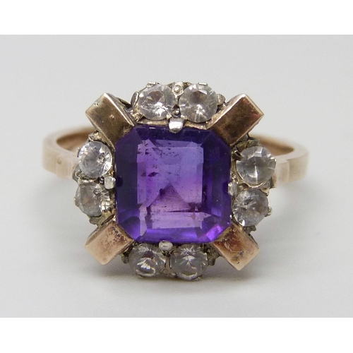 7064 - A yellow metal ring set with a central amethyst and white stones, 3g, M