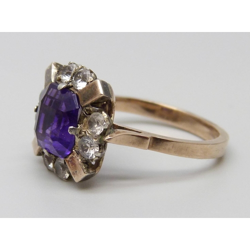 7064 - A yellow metal ring set with a central amethyst and white stones, 3g, M