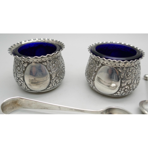 7295 - A pair of crested silver salts with blue glass liners, together with two salt spoons, (not matching)... 