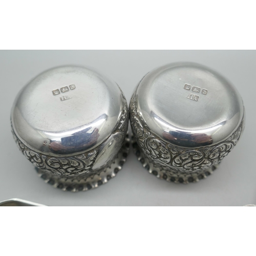 7295 - A pair of crested silver salts with blue glass liners, together with two salt spoons, (not matching)... 