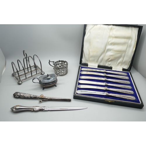 7296 - A collection of silver; cup holder, toast rack, mustard and salt spoon, 146g, a letter opener, tongs... 