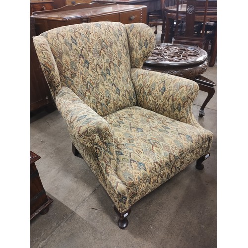 273 - An early 20th Century mahogany and fabric upholstered wingback armchair