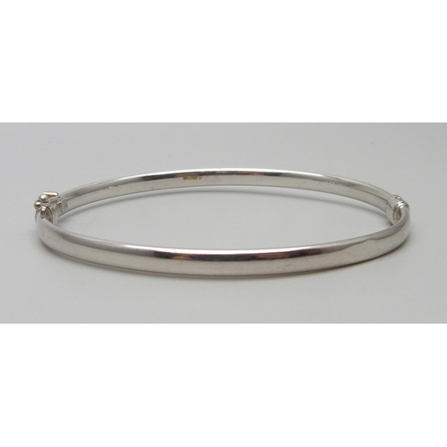 7023 - A 9ct white gold bangle, 3.8g, 52mm x 60mm, (dented)