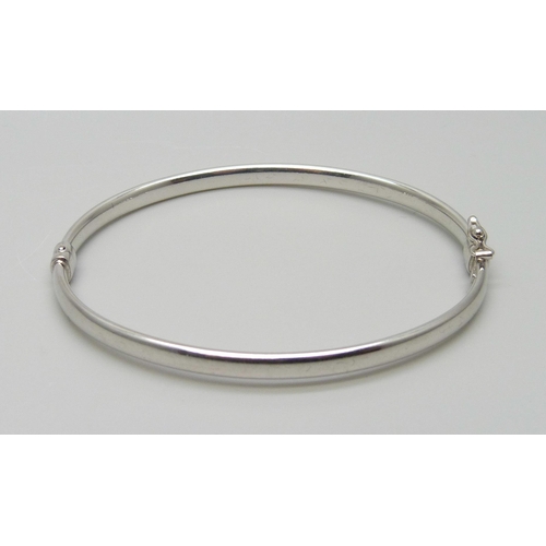 7023 - A 9ct white gold bangle, 3.8g, 52mm x 60mm, (dented)