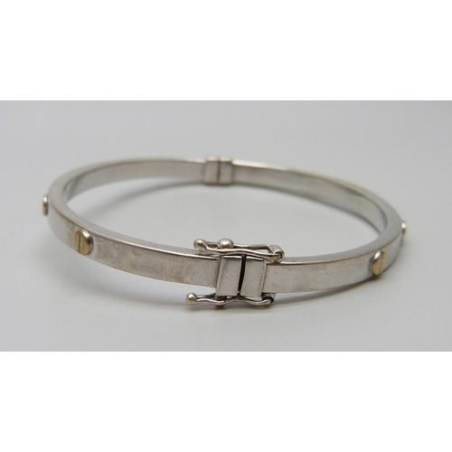 7028 - A 9ct gold bangle with screw detail, 6.9g, 51mm x 60mm