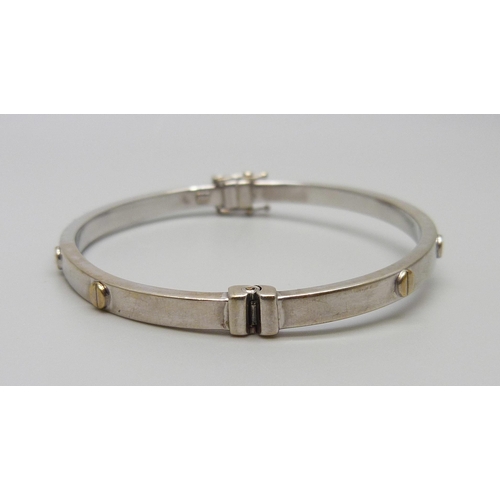 7028 - A 9ct gold bangle with screw detail, 6.9g, 51mm x 60mm