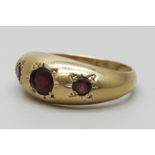 7076 - A 9ct gold ring set with three garnets, 2.9g, N