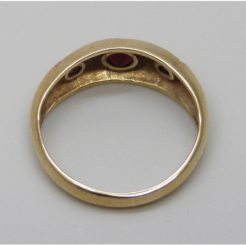 7076 - A 9ct gold ring set with three garnets, 2.9g, N