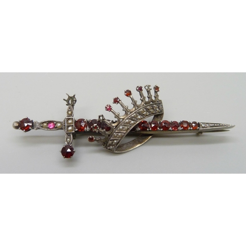 7118 - A silver brooch in the form of a sword and crown, set with seed pearls and garnets, 7.8cm, 10.8g