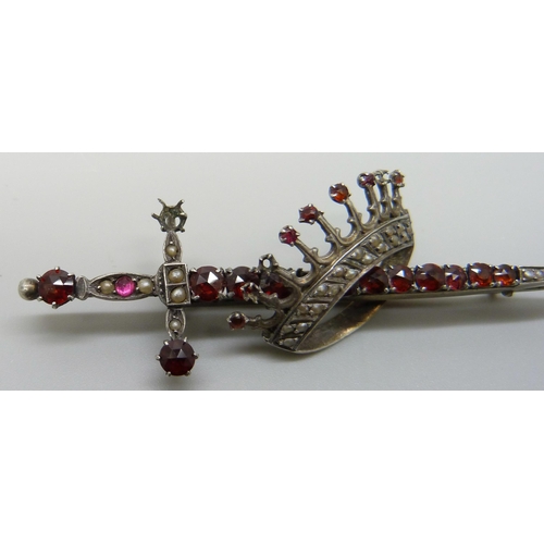 7118 - A silver brooch in the form of a sword and crown, set with seed pearls and garnets, 7.8cm, 10.8g