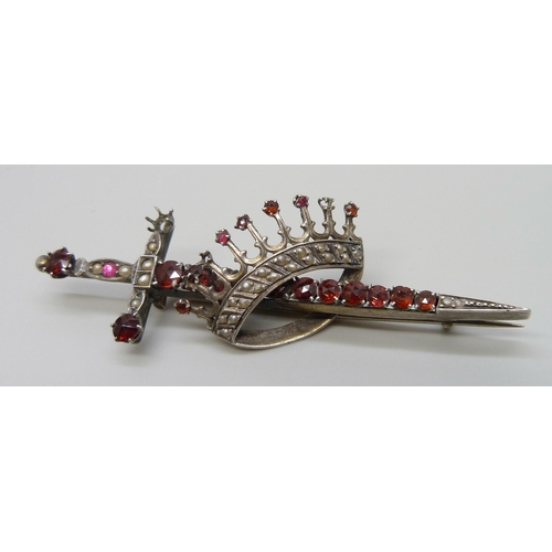 7118 - A silver brooch in the form of a sword and crown, set with seed pearls and garnets, 7.8cm, 10.8g