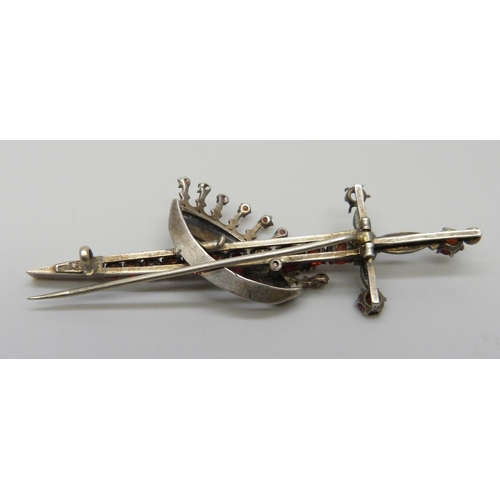 7118 - A silver brooch in the form of a sword and crown, set with seed pearls and garnets, 7.8cm, 10.8g