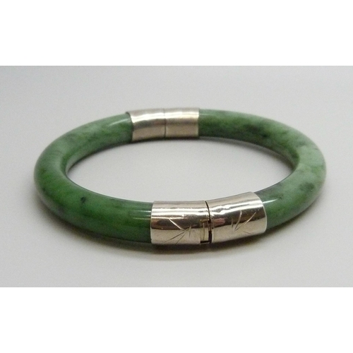 7126 - An Oriental nephrite bangle with white metal mounts, 43g, 6cm