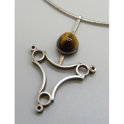 7137 - A Modernist silver pendant set with a cabochon tiger's eye stone, 5.5cm, on a silver collar chain, L... 