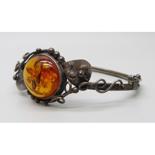 7138 - An Art Nouveau style silver and amber bangle, 14g