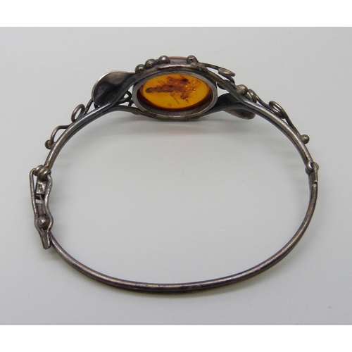 7138 - An Art Nouveau style silver and amber bangle, 14g