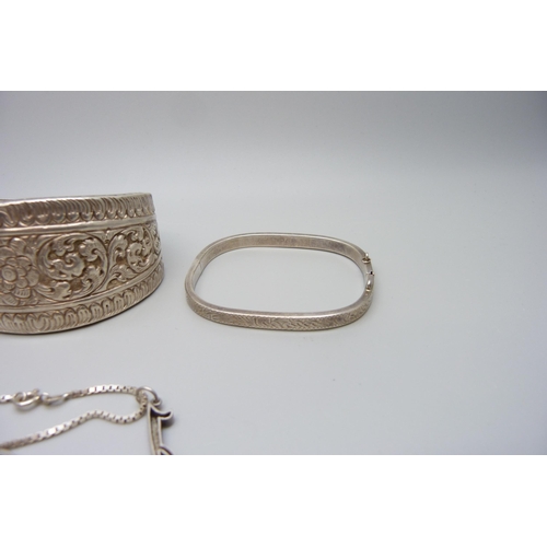 7157 - An Eastern white metal bangle, 4cm wide, a silver bracelet with charms and a pair of silver hoop ear... 