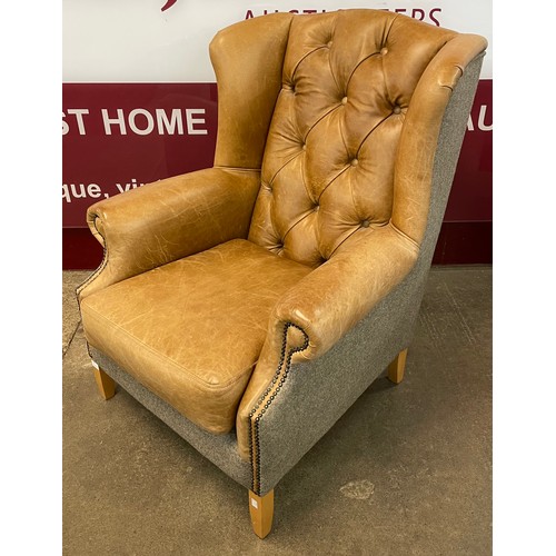 65 - A Chesterfield style tan leather and fabric upholstered wingback armchair