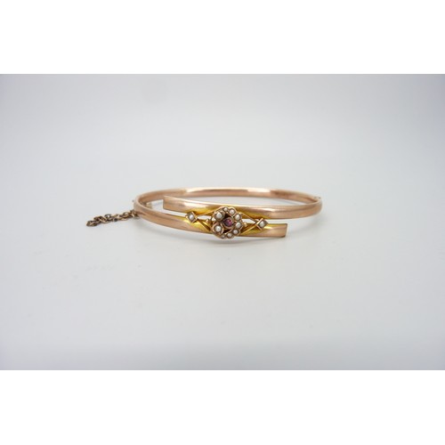 9018 - An early 20th Century 9ct rose gold bangle set with seed pearls and a ruby, boxed, 5.4g