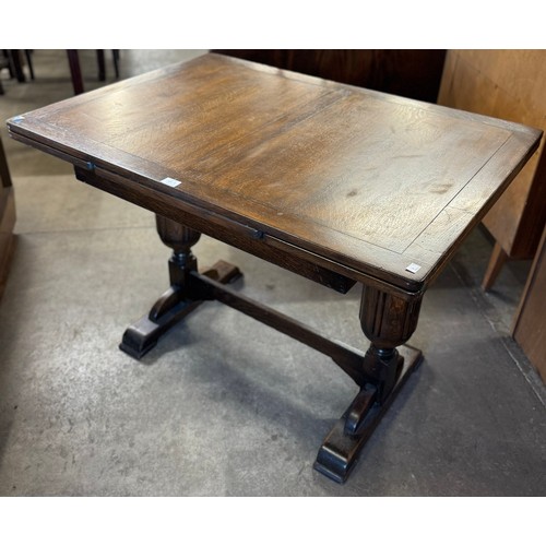 144A - An early 20th Century oak draw-leaf dining table