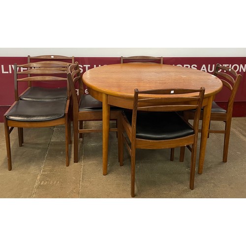 32 - A teak circular extending dining table and six teak and black vinyl dining chairs