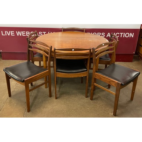 32 - A teak circular extending dining table and six teak and black vinyl dining chairs