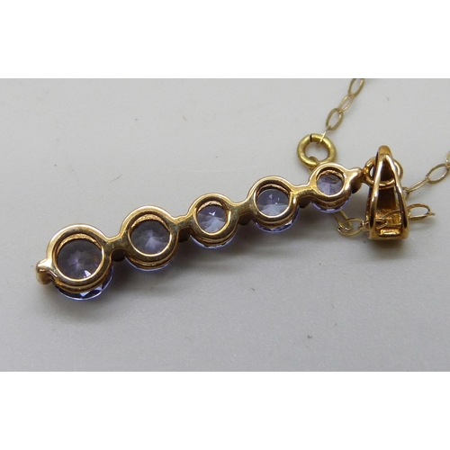 7038 - A 9ct gold five stone graduated tanzanite pendant on a fine 9ct gold chain, 1.5g