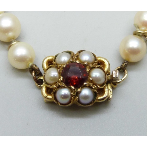 7045 - A cultured pearl necklace with 9ct gold clasp set with pearls and garnet, 43cm