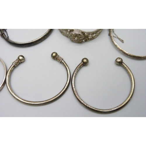 7079 - Four silver bangles, two white metal torque bangles and a filigree bangle, 86g