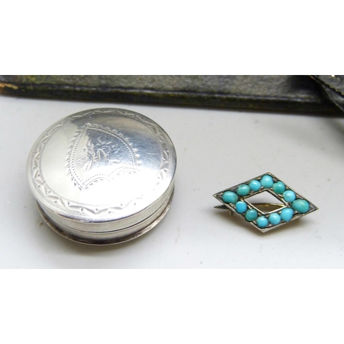 7142 - A white metal pill box with monogram, two turquoise set brooches, a pair of white metal fronted cuff... 