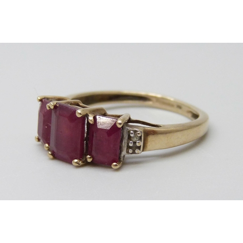 7001 - A 9ct gold three stone ruby ring set with diamonds, 2.4g, O