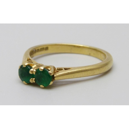 7051 - An 18ct gold and two stone emerald ring, 2.8g, K