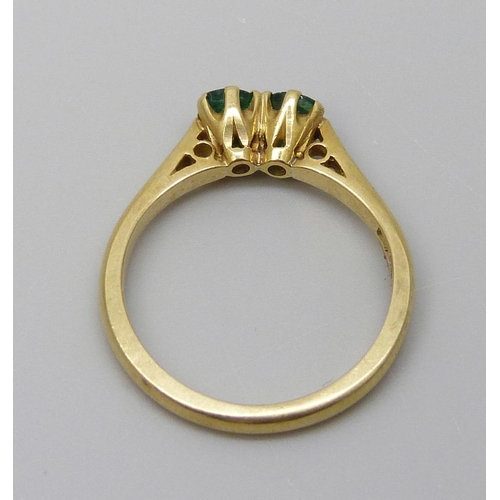 7051 - An 18ct gold and two stone emerald ring, 2.8g, K