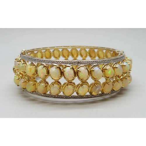 7090 - A 925 sterling silver gilt bangle set with over 40cts of Ethiopian opals, 57g