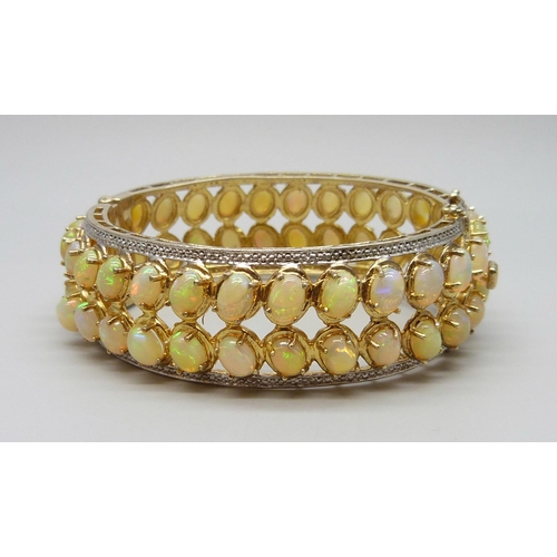 7090 - A 925 sterling silver gilt bangle set with over 40cts of Ethiopian opals, 57g