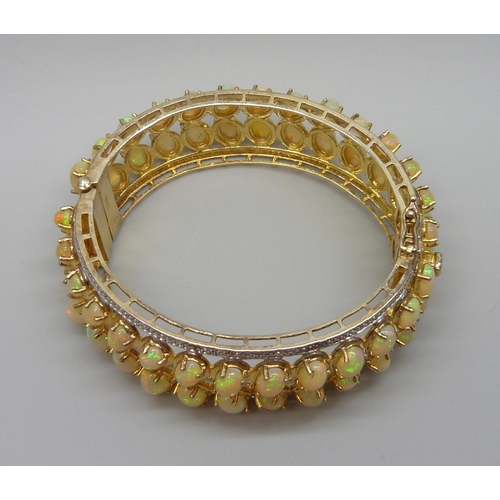 7090 - A 925 sterling silver gilt bangle set with over 40cts of Ethiopian opals, 57g