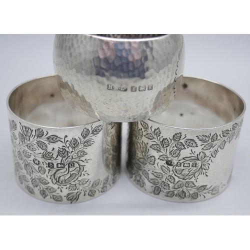 7351 - A pair of silver napkin rings, Birmingham 1910, and a hammered silver napkin ring, Birmingham 1909, ... 