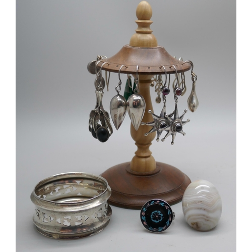 7355 - A wooden stand with silver earrings, a Scottish silver napkin ring and two silver rings, both size N