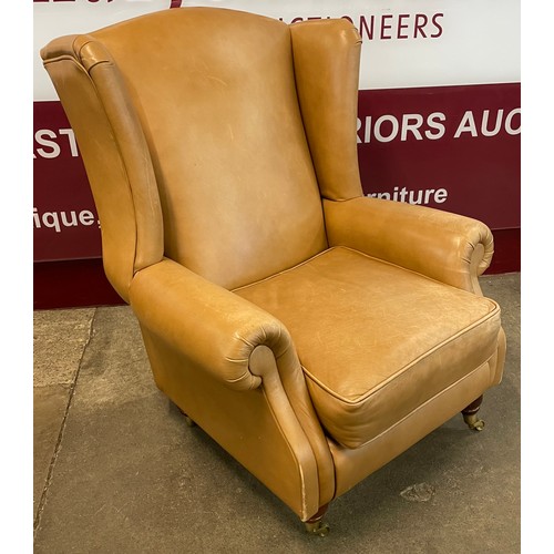 86 - A beech and tan leather wingback armchair