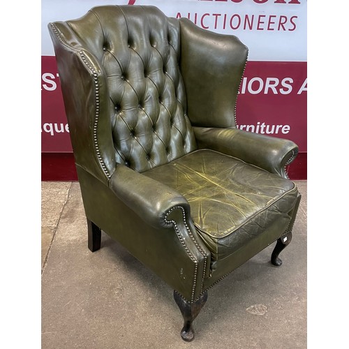 88 - A mahogany and green leather wingback armchair