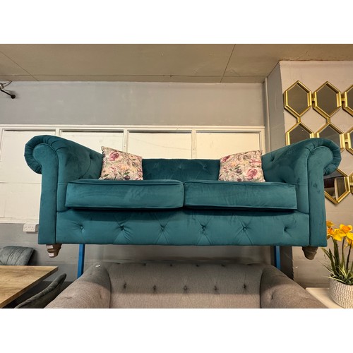 3025 - A turquoise velvet upholstered Chesterfield three seater sofa with patterned scatter cushions on tur... 