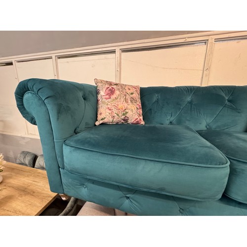 3025 - A turquoise velvet upholstered Chesterfield three seater sofa with patterned scatter cushions on tur... 