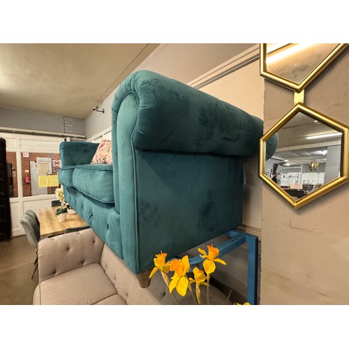 3025 - A turquoise velvet upholstered Chesterfield three seater sofa with patterned scatter cushions on tur... 