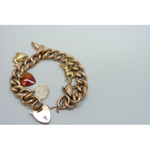 7033 - A 9ct gold curb chain bracelet with six charms, 4 gold, an agate heart and a silver 1906 Canadian 5 ... 