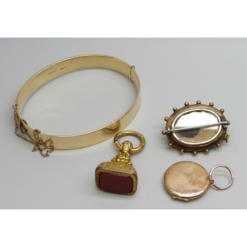 7037 - A 9ct gold metal core bangle, a gilt metal fob, a yellow metal memorial brooch and a yellow metal lo... 