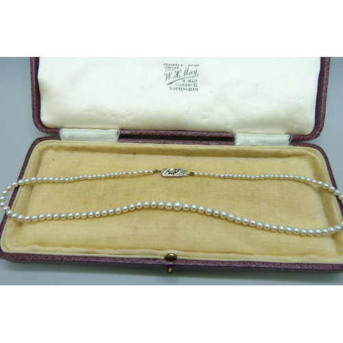 7086 - A string of pearls on a white metal clasp set with two old cut diamonds